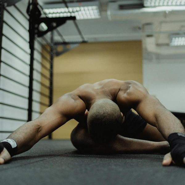 A person performing a dynamic stretching movement in a gym.
